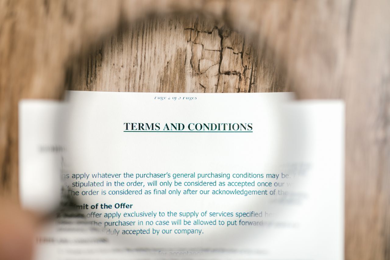 The Art of Drawing Readers In: Your attractive post title goes here Magnifying glass focusing on terms and conditions document on wooden surface.